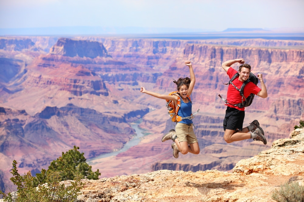 Happy,People,Jumping,In,Grand,Canyon.,Young,Multiethnic,Couple,On